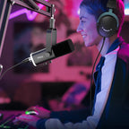 Person streaming or gaming with two monitors, a microphone, and headphones in a vibrant setting.